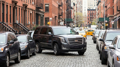 A luxury Cadillac Escalade car rental driving through the busy, skyscraper-lined streets of New York City