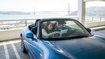 A car rental driving across the Golden Gate Bridge towards the sunny San Francisco skyline