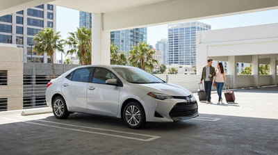 A red convertible car hire driving down a sunny, palm-lined street in a Florida city center