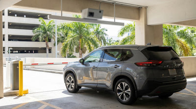 A car rental driving out of a multi-story parking garage exit with the Miami skyline visible