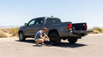 Driver checking the trunk of a car hire vehicle parked on a long, straight road in Texas