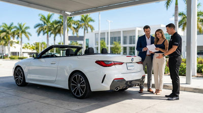 A convertible car hire driving down a sunny, palm-lined street in Miami