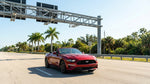 A car rental drives on a sunny Florida highway towards an electronic toll gantry with palm trees