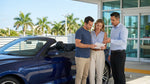 Traveler signing paperwork at a car rental desk in Miami with keys on the counter