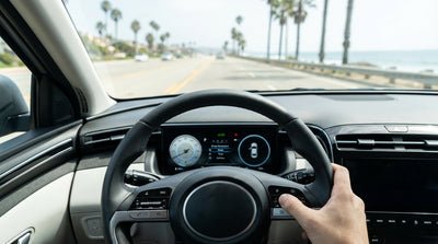 Driver's hands on a car hire steering wheel with cruise control buttons, driving on a sunny California highway