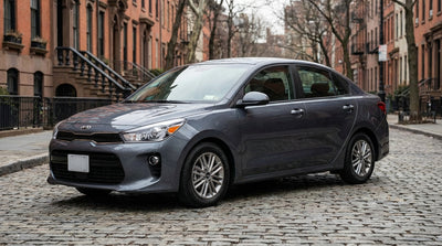 A modern car rental parked on a street in New York with the Brooklyn Bridge and city skyline in the background