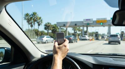 A car hire vehicle drives under a SunPass toll gantry on a sunny highway in Florida