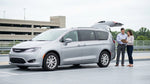 A couple driving a silver car rental along a tree-lined highway in Pennsylvania