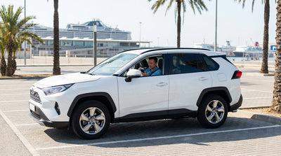 View from a car rental driving over the causeway to PortMiami with cruise ships docked under a sunny Miami sky