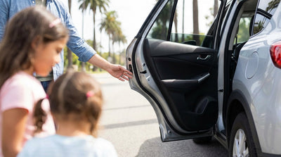 A driver examines the rear door of their car hire parked on a sunny street in California
