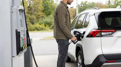 A driver holds a fuel nozzle at a Pennsylvania gas station, preparing to refuel their modern car hire