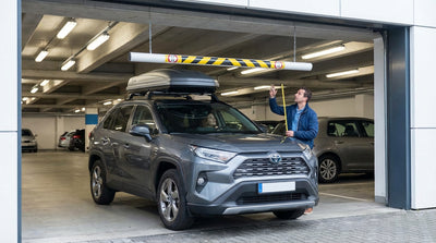 A car rental with a roof box stopped before a parking garage entrance on a busy street in New York City