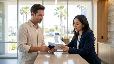 A person driving a convertible car hire along a sunny, winding coastal highway in California