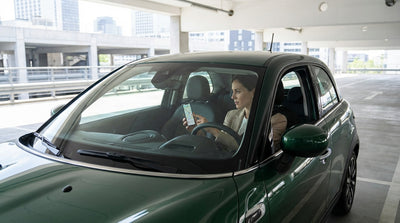 A driver using a car rental in New York checks Google Maps on their phone mounted on the dashboard