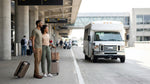Travelers standing with luggage at the car hire shuttle curb outside Philadelphia Airport in Pennsylvania