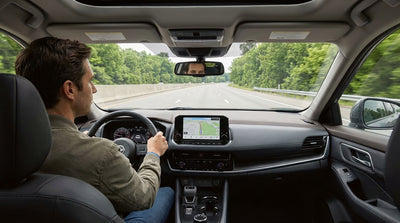 A car rental drives on the Pennsylvania Turnpike past a green highway sign for the next exit