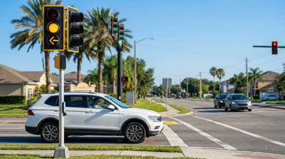 A car hire stopped at a sunny Orlando intersection with a flashing yellow arrow traffic light