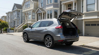 A car hire parked with an empty, open trunk on a steep San Francisco street with Victorian homes