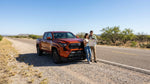 Driver inspecting the engine of a car hire broken down on a rural highway in Texas