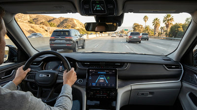 A person's hands on the steering wheel of a car hire vehicle driving on a sunny California freeway