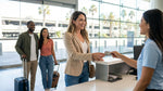Close up of a person handing a credit card to an agent at a car hire counter in California