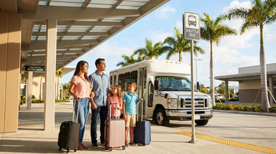 A smiling family with their luggage stands by a car hire vehicle on a sunny, palm-lined street in Orlando