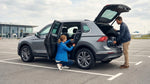 A person installs a child car seat in a New York car hire vehicle parked on a city street