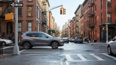 A car hire waiting at a red traffic light on a busy one-way street in New York