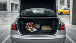A person checks the open trunk of a car rental in New York, looking at an emergency roadside kit