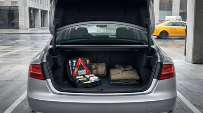 A person checks the open trunk of a car rental in New York, looking at an emergency roadside kit
