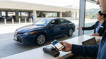 A traveler uses a smartphone to complete a car rental transaction at an SFO airport counter in San Francisco
