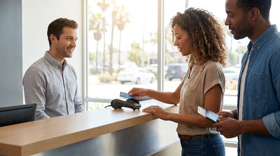 A customer handing a credit card to a car hire agent at a desk in California