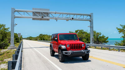 A rental car drives over the sunny Card Sound Road bridge from Miami, surrounded by the bright blue Florida water