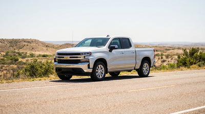 A pickup truck car hire driving down a scenic highway through the vast landscape of rural Texas