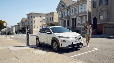 A modern electric car rental parked in an EV charging bay on a sunny, hilly street in San Francisco
