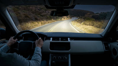 Driver's view from a car rental at night on a California road, dashboard controls illuminated