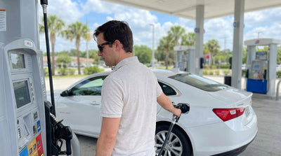 A driver refuels their car hire at a sunny gas station with palm trees in Orlando