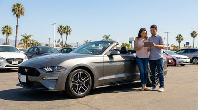 A modern car rental parked on a scenic road overlooking the sunny California coast and Pacific Ocean