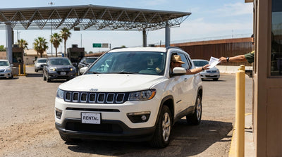 A convertible car hire driving on a scenic coastal highway on a sunny day in California