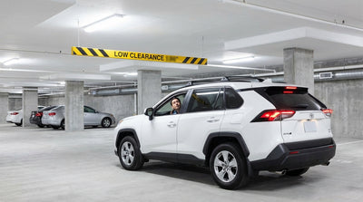 A car rental waits before entering a Las Vegas hotel garage with a low clearance sign visible above the entrance
