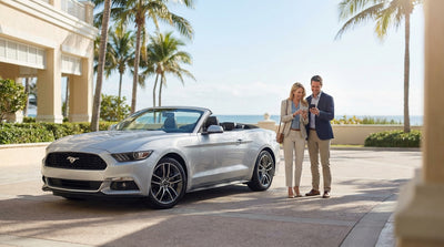 A luxury convertible car rental parked on a sunny Florida road with palm trees