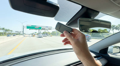 A white car hire drives on a sunny Florida highway under a SunPass electronic toll gantry