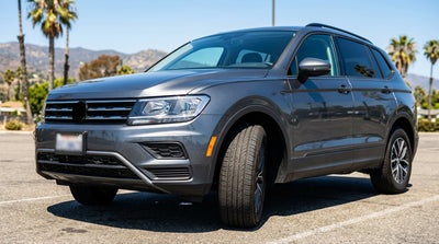 Driver inspects the tire of a car rental on a sunny coastal road in California