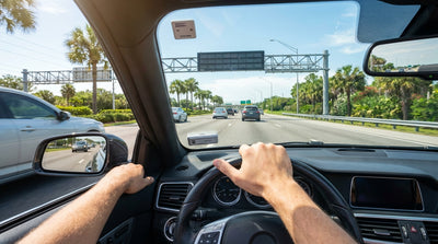 A car rental drives toward a SunPass toll gantry on a wide, sunny highway in Orlando
