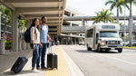A purple car rental shuttle bus collects travelers from the curb outside of the LAX Terminal 4 arrivals area