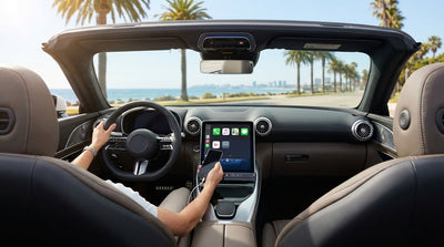 A phone showing a map on a car rental dashboard screen while driving down a palm-lined street in Los Angeles