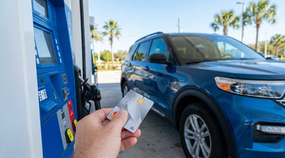 A person refueling their white car hire at a sunny Orlando gas station pump