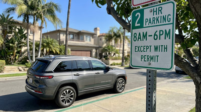 A car hire vehicle parked on a sunny, residential Los Angeles street with a permit parking sign in the foreground