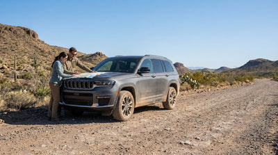 A Texas car hire vehicle driving down a dirt road with vast desert mountains in the background