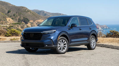 A convertible car rental driving on a scenic coastal highway in California with the ocean on one side